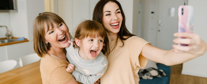 White family laughing while taking selfie photo on mobile phone
